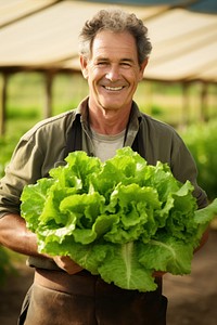 A happy Farmer holding fresh butter head lettuces gardening vegetable outdoors.