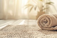 Calming and warm domestic scene with a focus on a neatly rolled-up light brown towel resting on a textured beige surface that appears to be a mat or tablecloth blanket rug home decor.