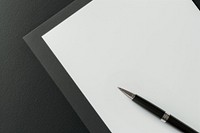 Black pen on blank white paper, simple and elegant. Pen and paper for writing, drawing, or notes. Minimalist pen and paper setup on dark background.