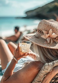 A woman in a sun hat sipping a cocktail accessories accessory beverage.