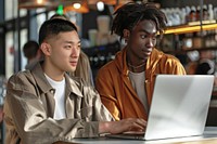 2 young colleagues use laptop at cafe computer togetherness portability.