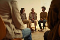 Photo of a group of 5 people seat in therapy session room conversation furniture.