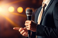 Motivational speaker with microphone performing on stage finger adult hand.