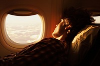 A person sleeps sitting near the window of a plane adult contemplation photography.