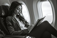 An Hispanic businesswoman sitting on an airplane seat and writing reading window adult.