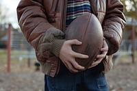 Person holding football clothing apparel jacket.