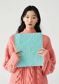 Holding a turquoise paper sheet sweater clothing knitwear.
