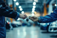 Mechanic handing car keys to his customer clothing apparel person.