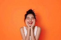 Asain woman hands cupping face happy surprised laughing.