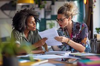 Photo of two woman working together document sitting table.