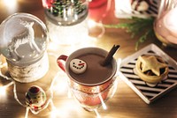 Festive hot chocolate in a red mug with a snowman marshmallow, surrounded by warm lights. Cozy holiday drink, perfect for winter nights and festive gatherings. Christmas and winter background.