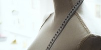 A tailor's mannequin with a measuring tape draped over it, symbolizing fashion design, sewing, and tailoring. Mannequin and tape in workspace. Fashion design and clothing brand. Fashion designer