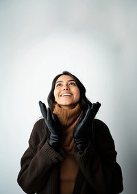 A joyful american indian woman in her 30s in winter gloves sweater smiling.