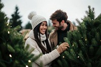 A couple buy a big fresh christmas tree at pine tree farm together clothing smiling lights.