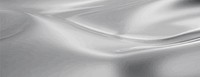 A silver background with a smooth, metallic texture. The background features flowing, reflective patterns. Silver color dominates the background. Smooth elegant silk fabric texture background