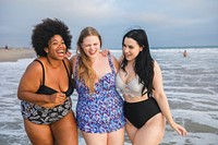 Diverse three women enjoying a day at the beach, laughing and walking by the ocean. Women friends wear swimsuits and appear joyful and carefree, embracing the beach vibes. Women enjoy at beach