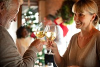 Elderly man and woman toasting with wine glasses, celebrating together. Festive atmosphere, joyful expressions, holiday cheer, and warm smiles. Family toasting and celebrating at Christmas party.