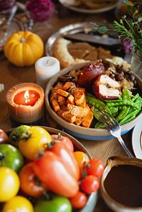 A festive table with colorful vegetables, sweet potatoes, and fruits. Candles and pumpkins add warmth. Vegetables and fruits create a vibrant, inviting scene. Festive autumn and Thanksgiving dinner.