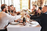 Group of diverse people celebrating at a new year dinner, toasting with champagne. Smiling guests enjoy a joyful gathering, sharing a celebratory meal. Friends celebrating at New Year's dinner party.