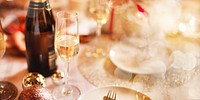 Festive dining table with champagne, glasses, sparkling decorations. Elegant champagne celebratory atmosphere. Champagne and glass on dining table with elegant sparkle decor, new year celebration