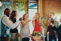 Group of diverse adults celebrating at a party. Smiling men and women, dressed elegantly, raise glasses. Festive atmosphere with diverse friends enjoying together. Group celebration and party.