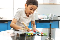 Young boy focused on a science project in a classroom. The boy is engaged in learning, using colorful materials. Education and creativity in a school setting. Education and knowledge concept.