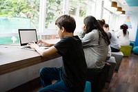 Students studying in a modern library. Young people focused on laptops. Diverse group learning in a bright, open space. Education and technology in action. Students learning on laptops, computer class