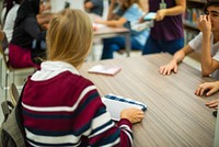 Students sitting at a table in a classroom setting, engaged in discussion. Diverse group of young people, focusing on learning and collaboration. Diverse students discussing and learning in classroom.