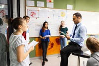 Group of students and a teacher in a classroom discussing. Diverse student group learning in class. Students learning, discussion with teacher in class. High school students with teacher in class