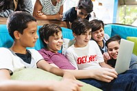 Group of boys, diverse ethnicities, gathered around a laptop, smiling and engaged. Boys enjoying technology, boys sharing a moment, boys learning through digital devices and technology. 