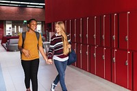 Two people walking in a hallway with red lockers. They are smiling and talking. The hallway is bright and spacious with a modern design. Friendship in school.