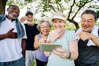 Group of diverse seniors laughing together outdoors, enjoying a moment. Seniors sharing joy, looking at phone. Happy seniors, diverse and joyful in the park. Group of diverse senior people in park.