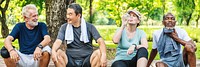 Group of diverse seniors resting after exercise in a park. Diverse seniors smiling and chatting, with towels and water bottles. Outdoor fitness and friendship. Group of healthy diverse senior people.