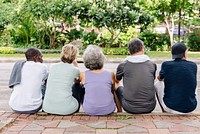 Diverse senior sit in park, back view photo. Diverse group of senior friends enjoy outdoors trees after exercise in park. Diverse group of healthy senior relax in park after exercise, back view photo