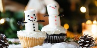 Festive cupcakes with marshmallow snowmen, surrounded by snow and pinecones. Snowmen cupcakes, holiday treats, and festive decor create a winter wonderland. Festive Christmas snowman cupcakes.