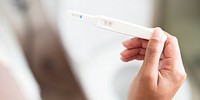 Close-up of a hand holding a pregnancy test. The test shows a positive result. Pregnancy test, positive result, hand holding, close-up view. Woman holding a pregnancy test.