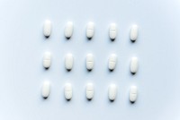 White pills arranged in a grid on a light background. Medication, pills, and tablets are evenly spaced. Pharmaceutical, health, and medicine concept. Healthcare and medicine background.