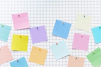 Colorful sticky notes on a grid background. Sticky notes in pink, blue, yellow, and green. Grid pattern enhances the sticky notes' vibrant color background. Colorful office notes background.