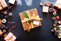 Festive gift box with pinecones and ribbon on a dark table. Holiday gift, wrapped gift, and decorative pinecones create a cozy, festive atmosphere. Festive holiday gift.