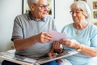 Elderly couple looking at photos. Senior man and woman sharing memories. Happy elderly couple enjoying time together. Senior couple with photo album. Senior man and woman looking at photos in album.