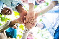 Diverse group of people joining hands in a circle, symbolizing teamwork and unity. Hands of different ethnicities and genders coming together in harmony. Happy students stacking hands in teamwork.