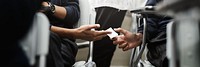 Two people discreetly passing a note in a classroom setting, focusing on hands and paper. The scene suggests secrecy and communication in a learning environment. Cheating on exams.