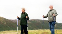 Senior couple hiking with poles in a scenic landscape. Seniors enjoying nature, hiking in the hills. Outdoor activity for elderly, exploring nature together. Senior couple hiking with sticks in nature