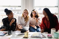 Group of diverse business women collaborating at table with tablet, coffee cups, and notebooks. Casual setting with a focus on women teamwork and discussion. Diverse business women discuss together