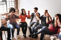 Diverse group of people sitting in a circle, holding hands, and smiling. Mixed genders and ethnicities, showing unity and connection. Diverse people sitting in a circle of support from community.