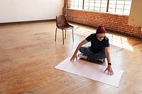 Startup business man sits on wooden floor, arranging a large sheet of paper. Empty room with brick walls and a chair. Focus on creativity and planning. Startup business man working on floor.