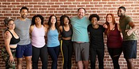 Diverse group of men and women in active wear, smiling and standing together. Diverse men and women in active wear posing together. Happy diverse people in fitness attire embracing together. Fitness