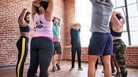 Group of diverse people stretching in a gym. Men and women in workout attire, exercising together. Fitness, exercise, and stretching in a bright studio. Diverse people exercising together at gym.