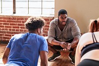 Fitness instructor guides a workout session. The instructor, wearing a gray hoodie, leads the exercise. The workout session is in a bright, spacious room. Fitness instructor and coach training people.