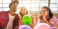 A joyful celebration scene featuring three friends all enjoying party hats, balloons, and festive noisemakers at a vibrant gathering. Group of friends joyful with party 